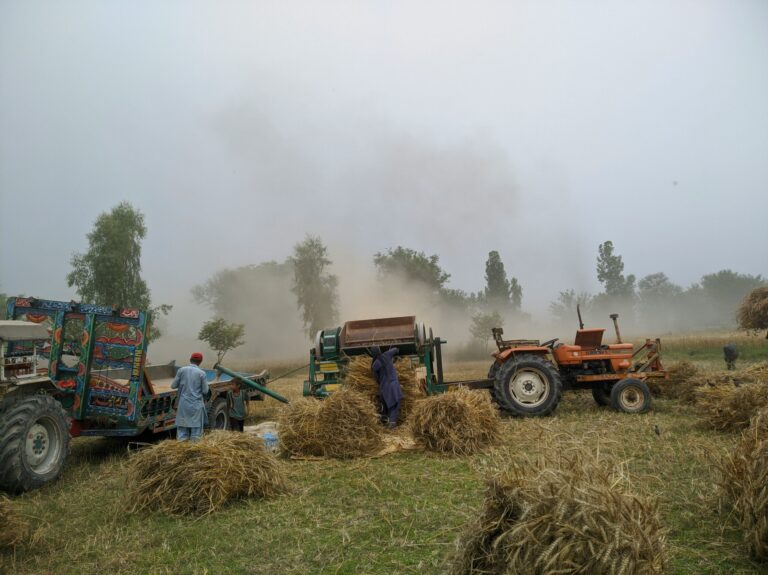 A field with tractors working in a dusty environment.