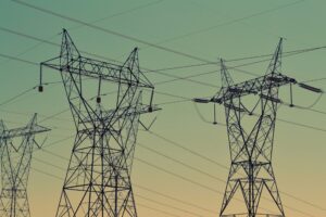 Electricity transmission towers against a sunset sky.
