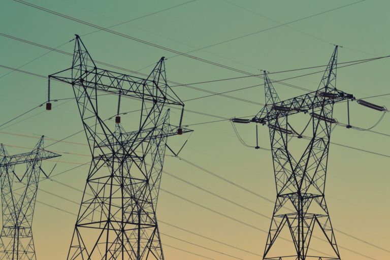 Electricity transmission towers against a sunset sky.