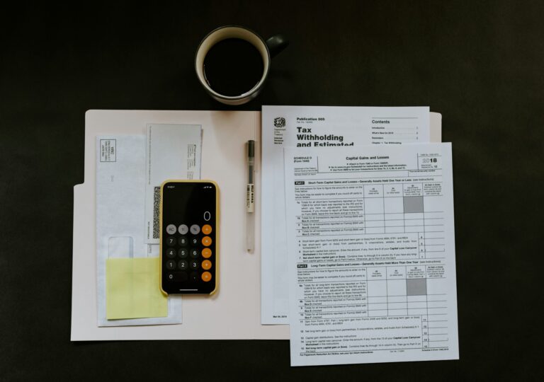 A dark wooden table with tax documents, a phone, and a coffee cup.