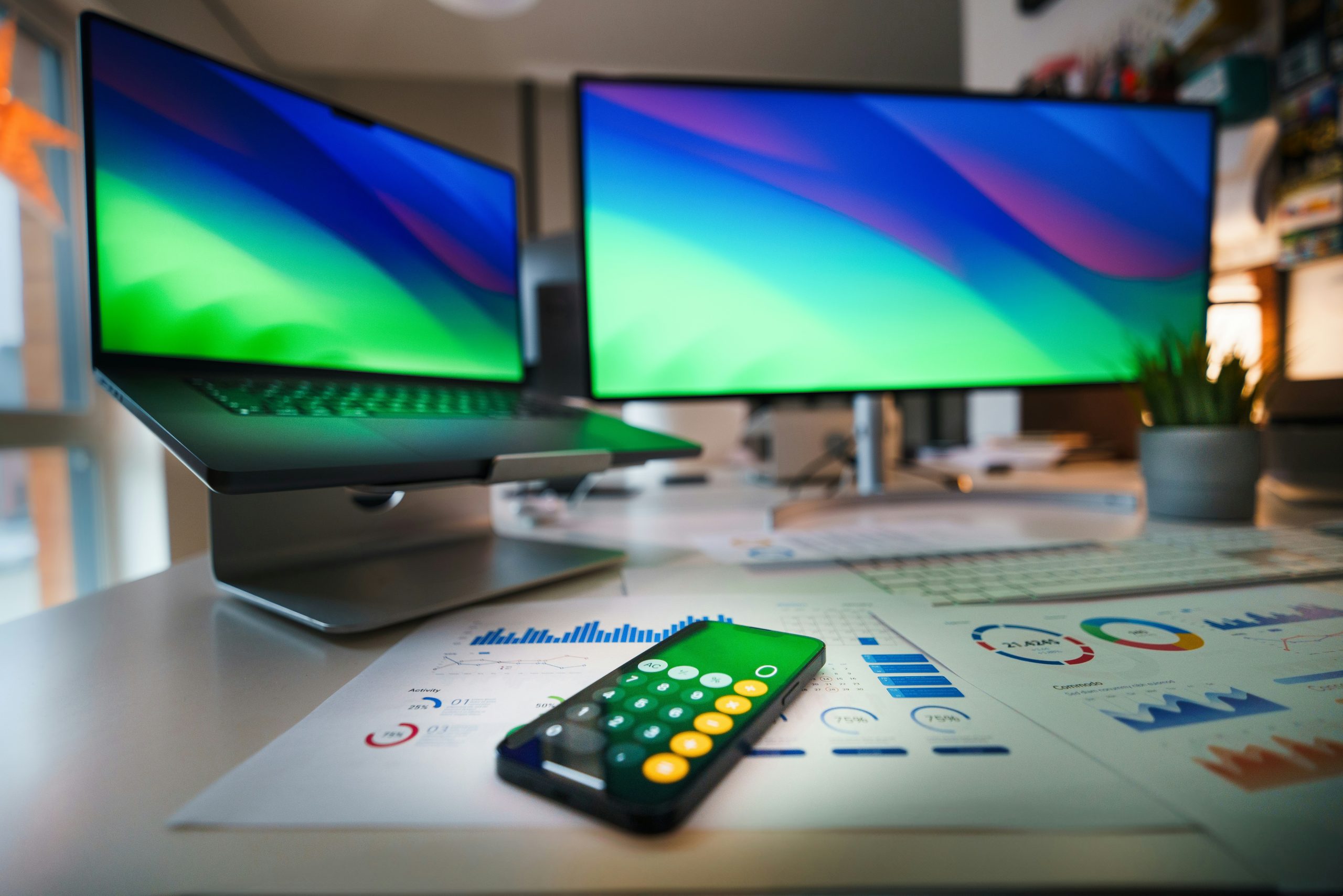 A modern desk setup with dual monitors, financial charts, and a calculator.