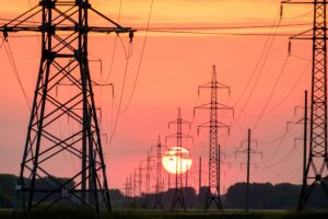 High-voltage power lines against a sunset sky.