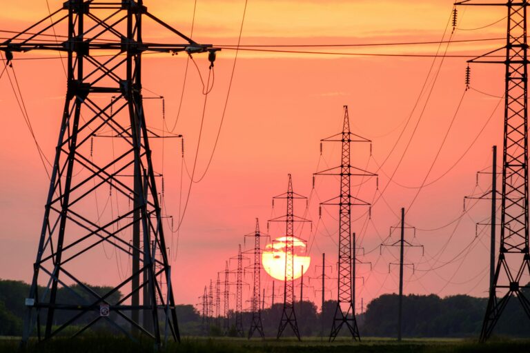 High-voltage power lines against a sunset sky.